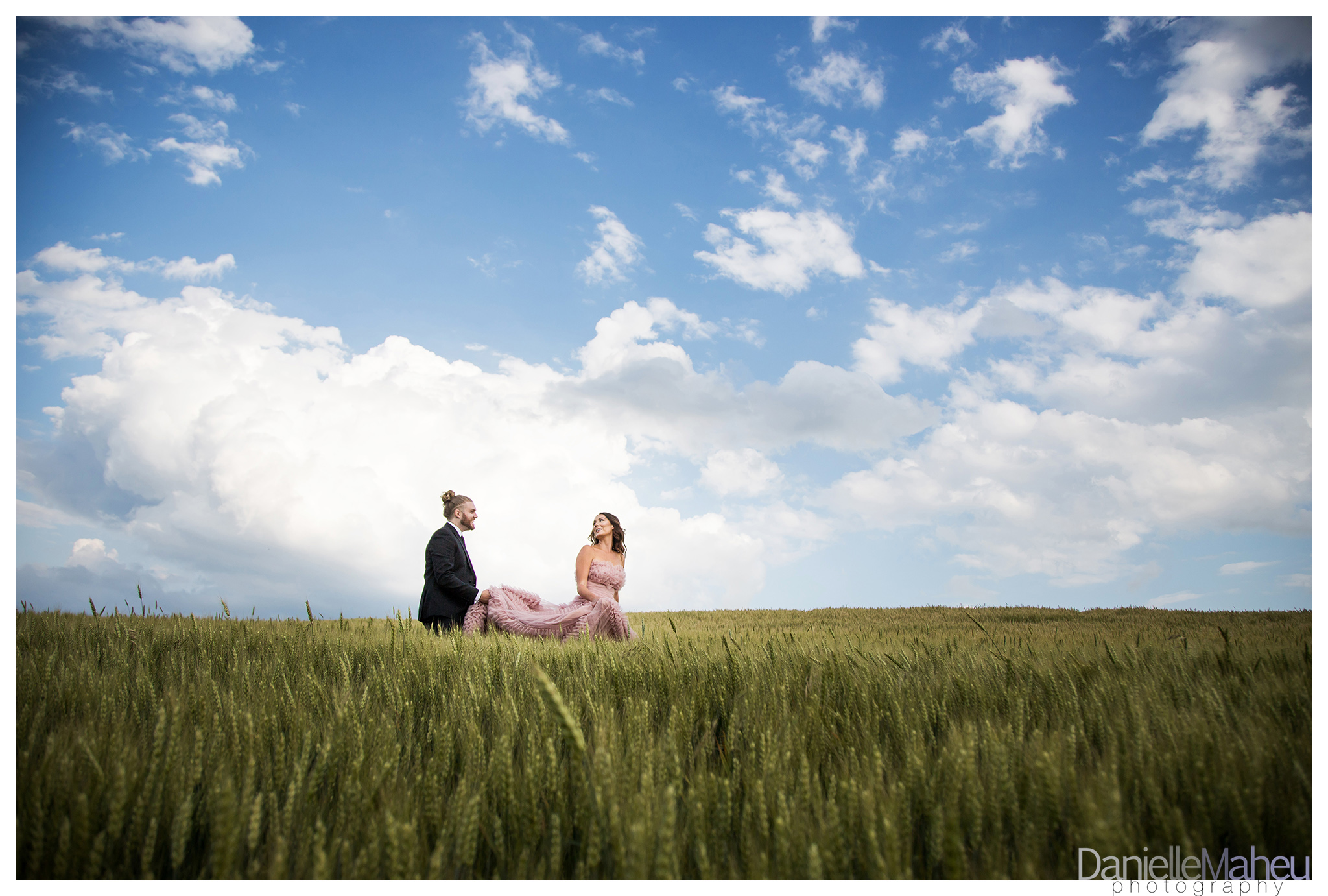 Engaged couple walking in a wheat field in a pink designer gown at Ivy Ridge wedding venue in Thornton Ontario