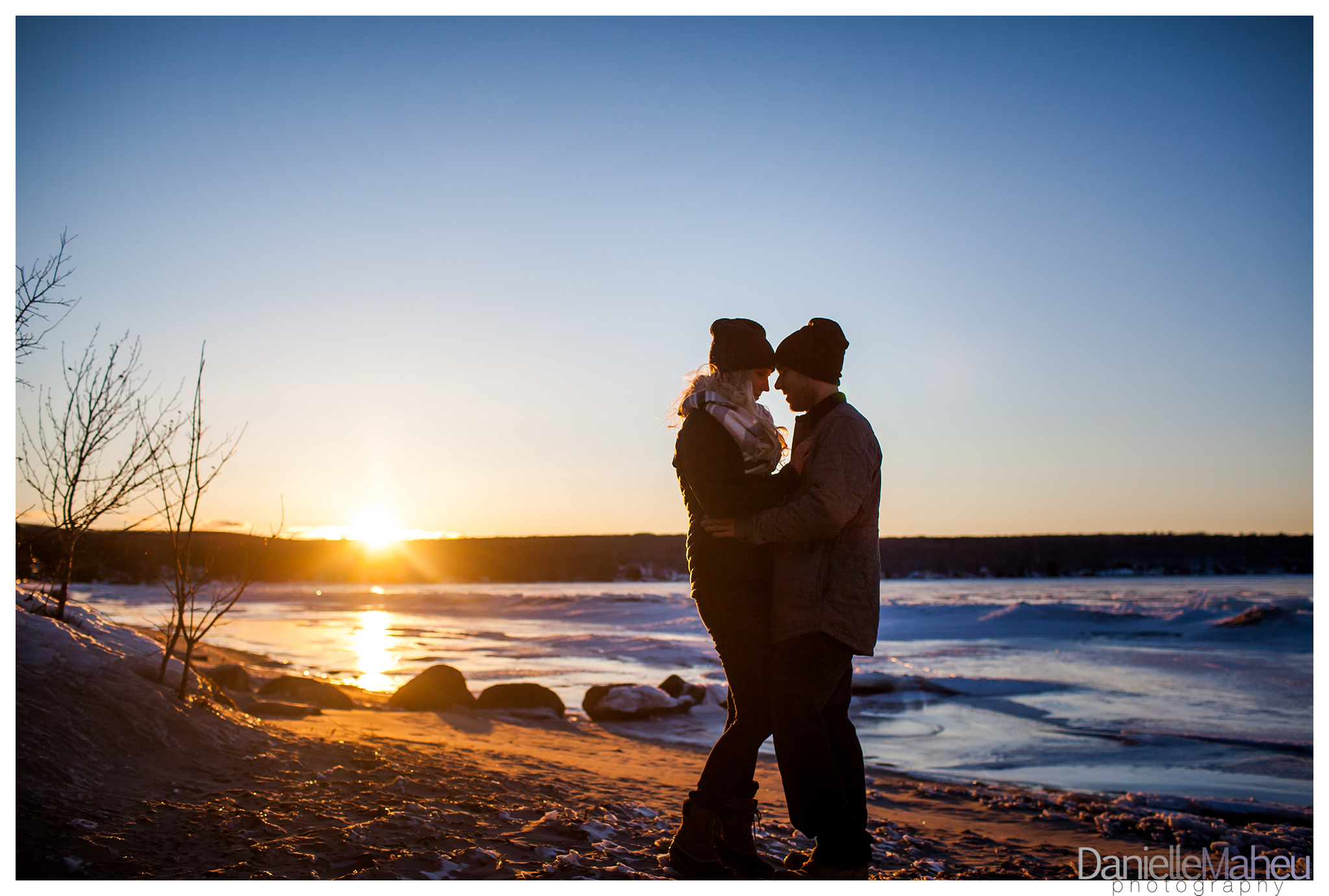 Engaged couple embrace on a beach in winter