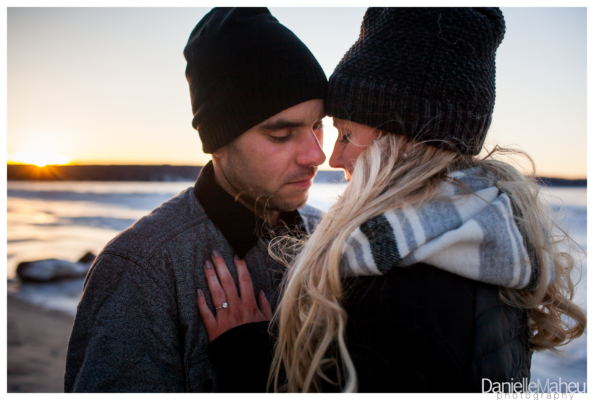 Engaged couple embrace on a beach in winter
