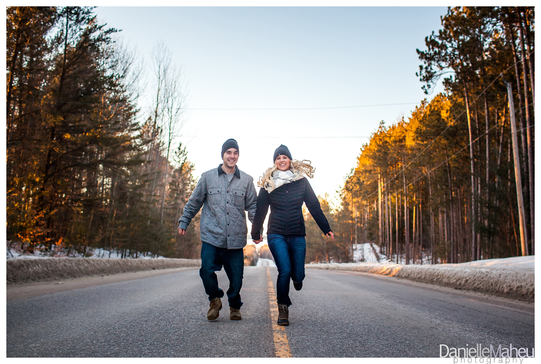 Engage couple in winter run down county road holding hands